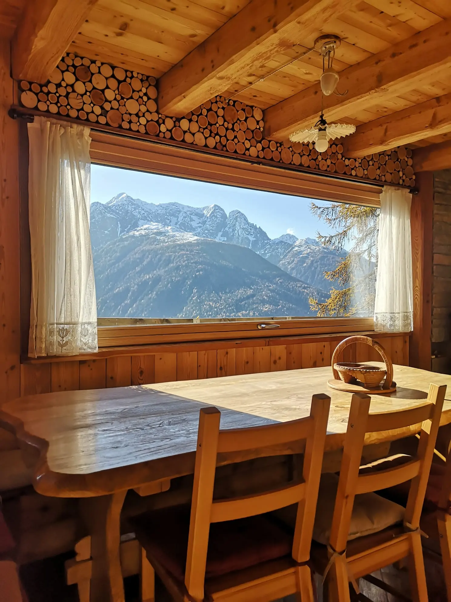 Il tavolo in legno della baita davanti alla finestra sulle montagne
