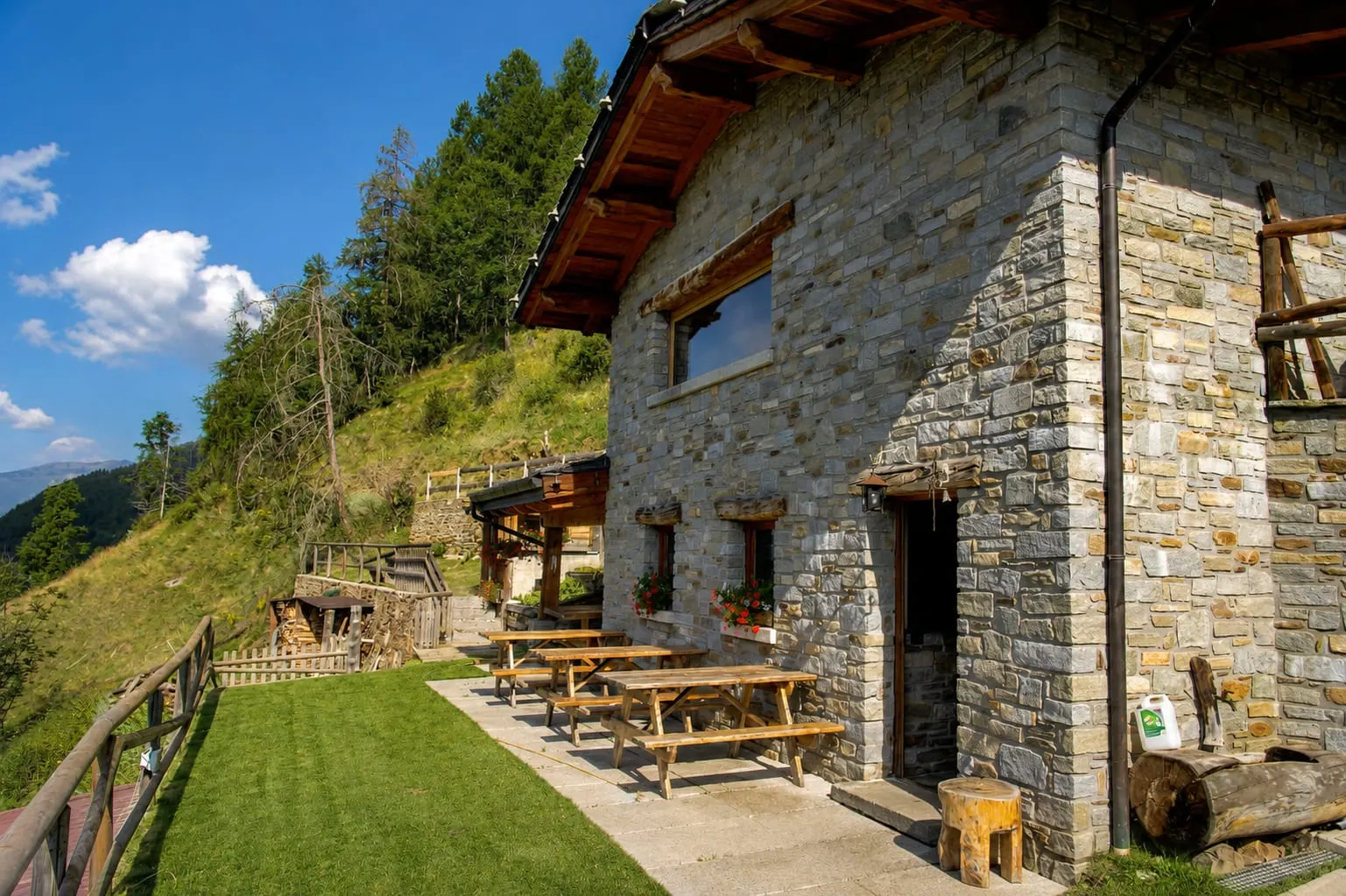 Baita & Chalet La baita in pietra con i tavoli sul prato, tra i larici a 1550 metri